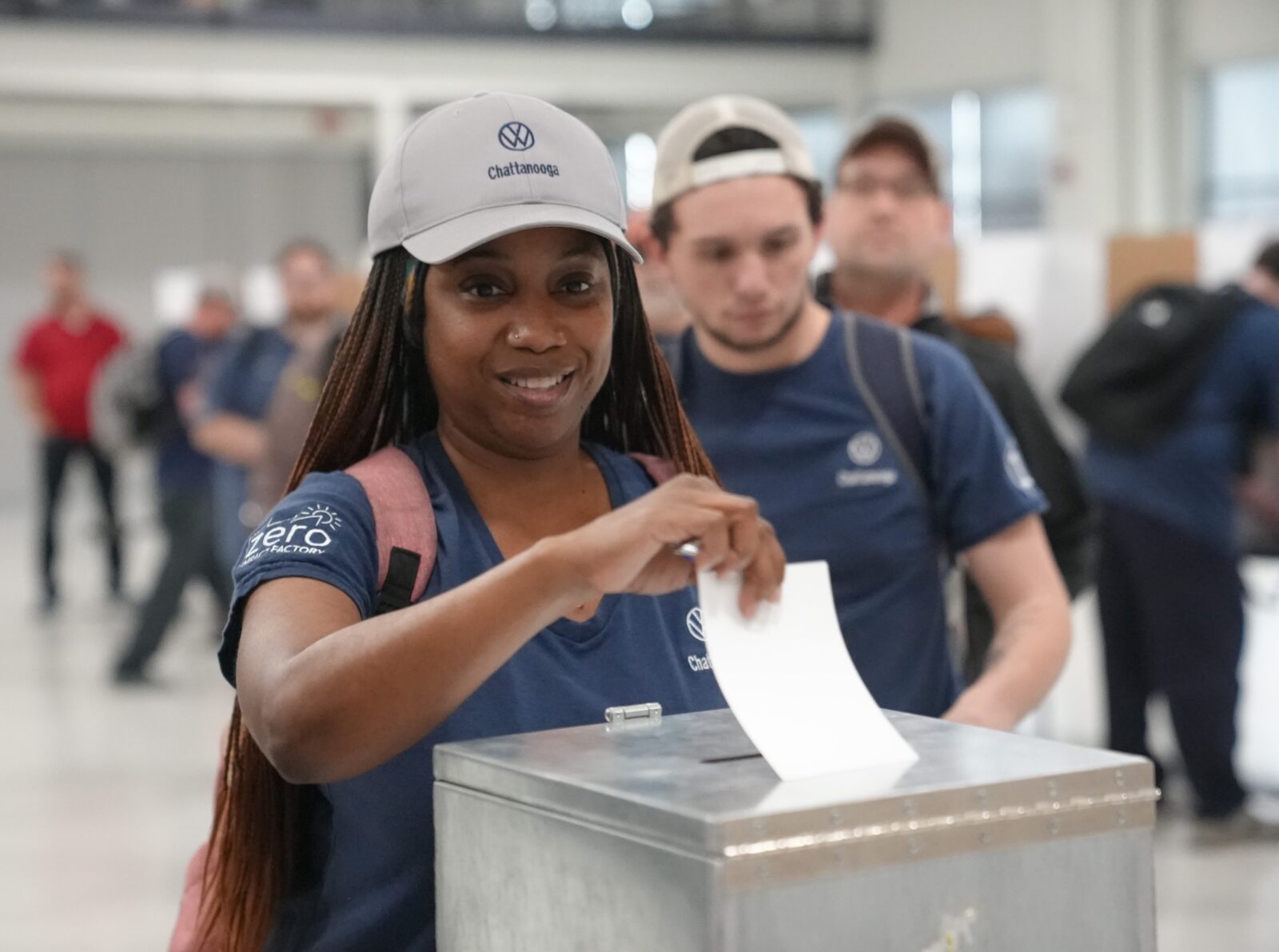 A worker casting her ballot during the Volkswagen Chattanooga union contract ratification vote, with fellow workers visible in the background.