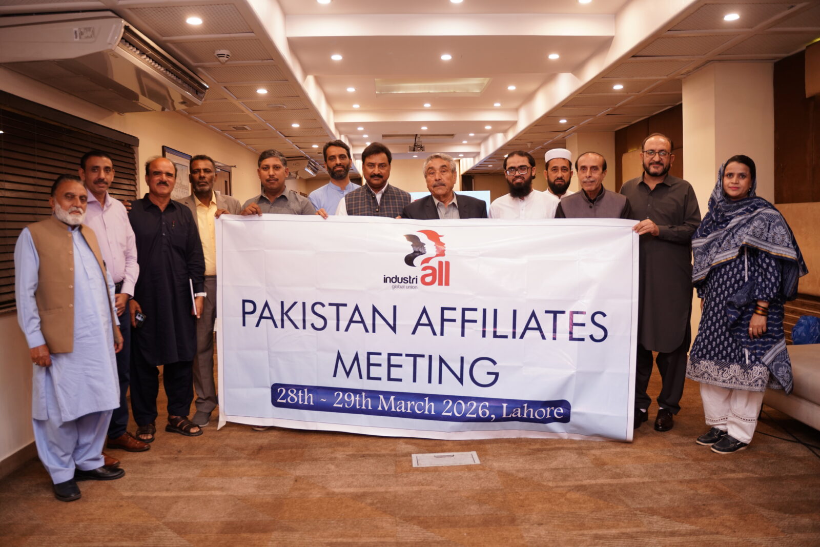 Pakistan affiliates meeting participants hold an IndustriALL banner in Lahore, 28–29 March 2026