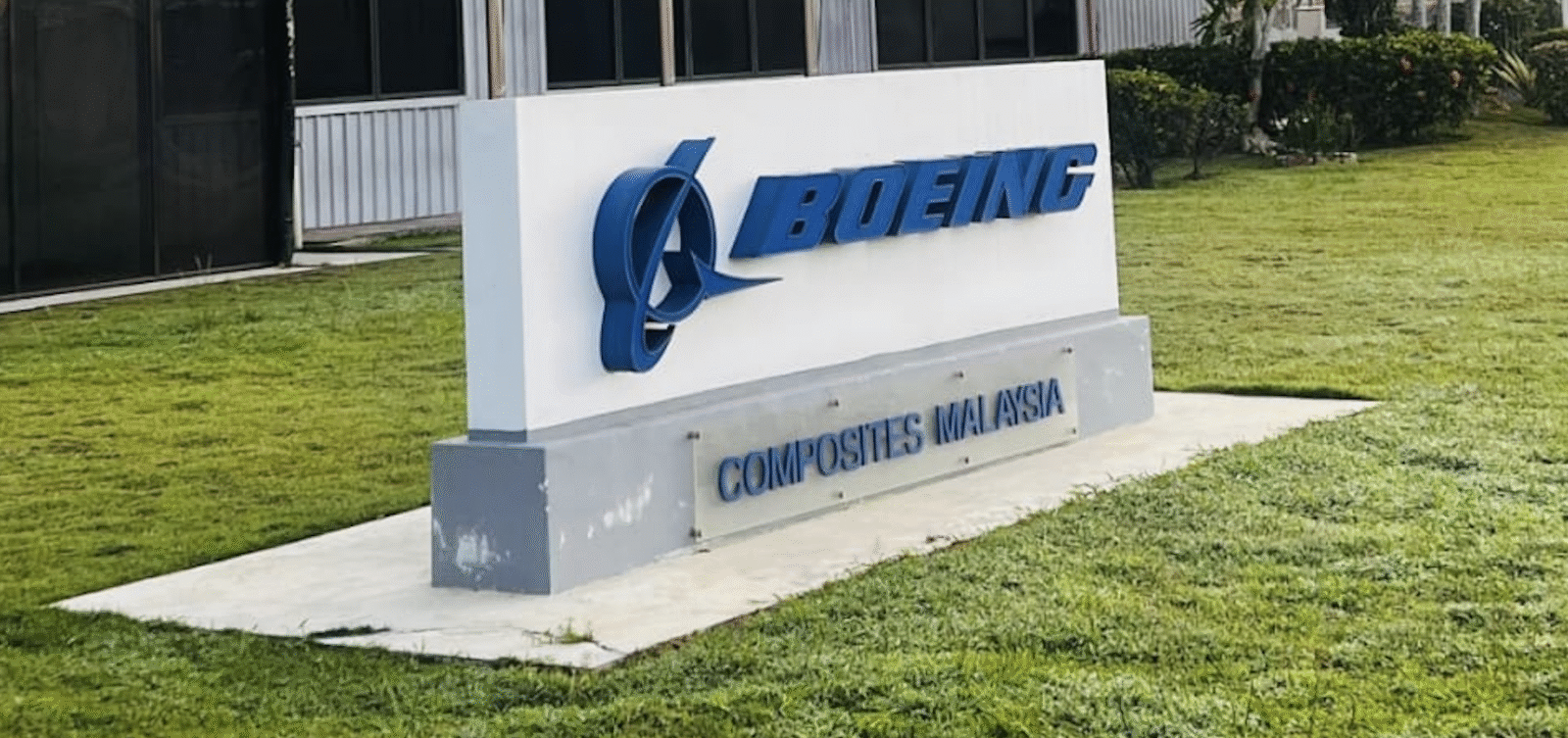 Boeing Composites Malaysia signage outside the company's manufacturing facility, with the Malaysian flag flying alongside two other flags