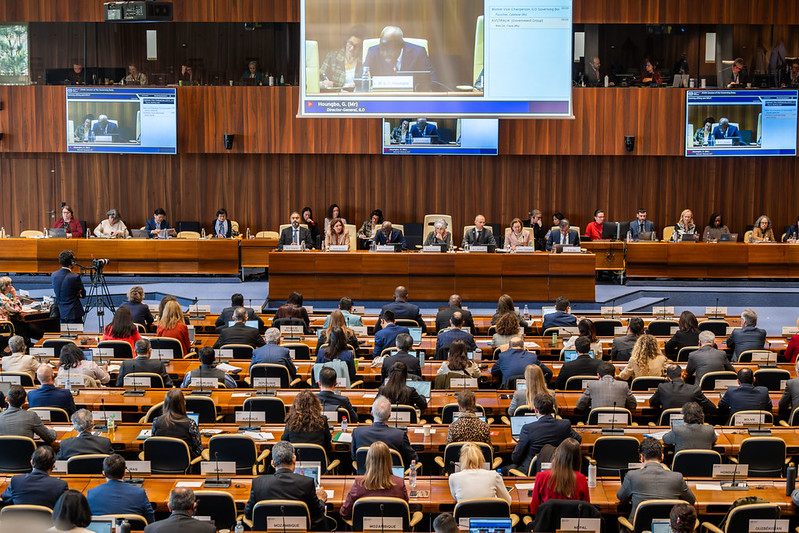 Delegates seated in the ILO governing body chamber during the opening of the 356th session, with director-general Gilbert Houngbo addressing the meeting on screen