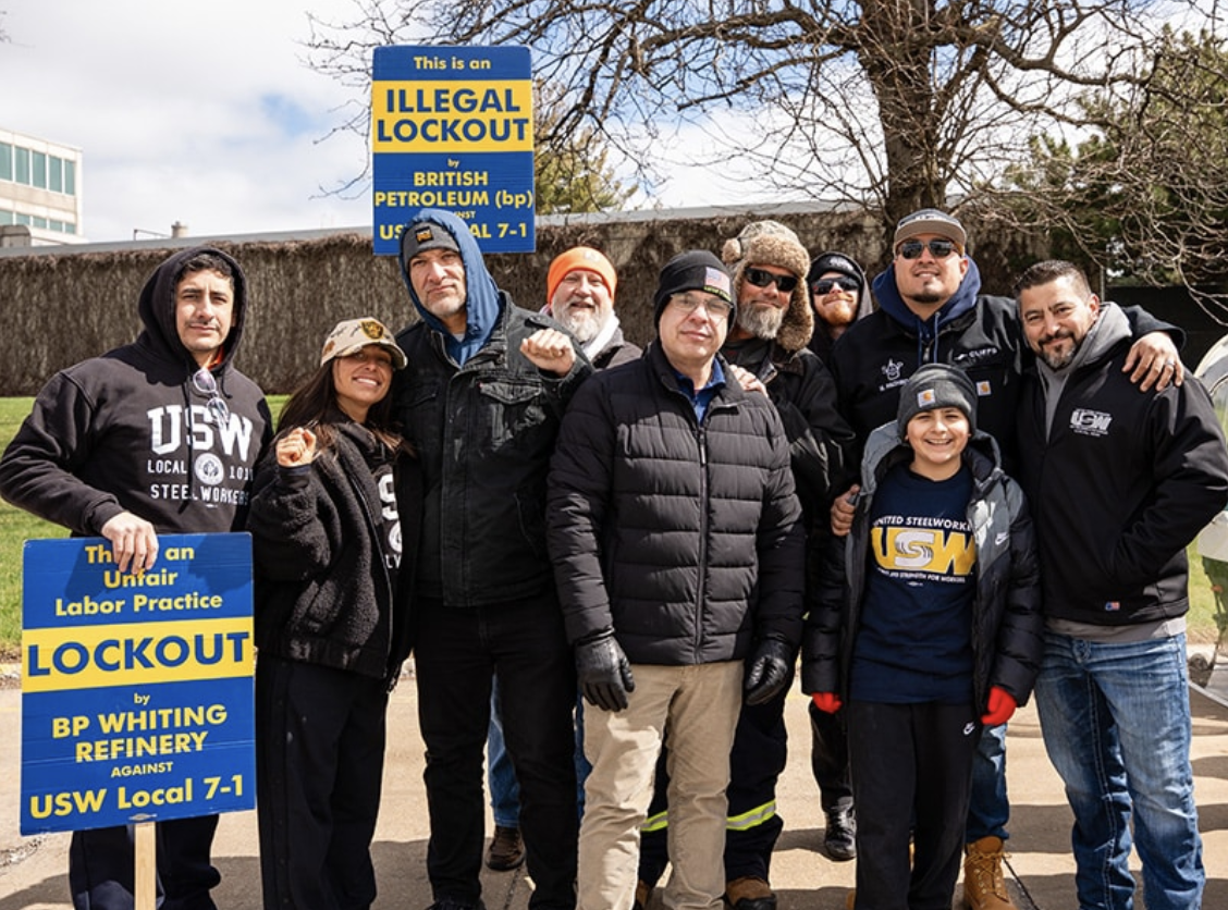  USW members and families picket outside BP's Whiting refinery in Indiana, holding signs reading "Illegal Lockout" and "Unfair Labor Practice Lockout"