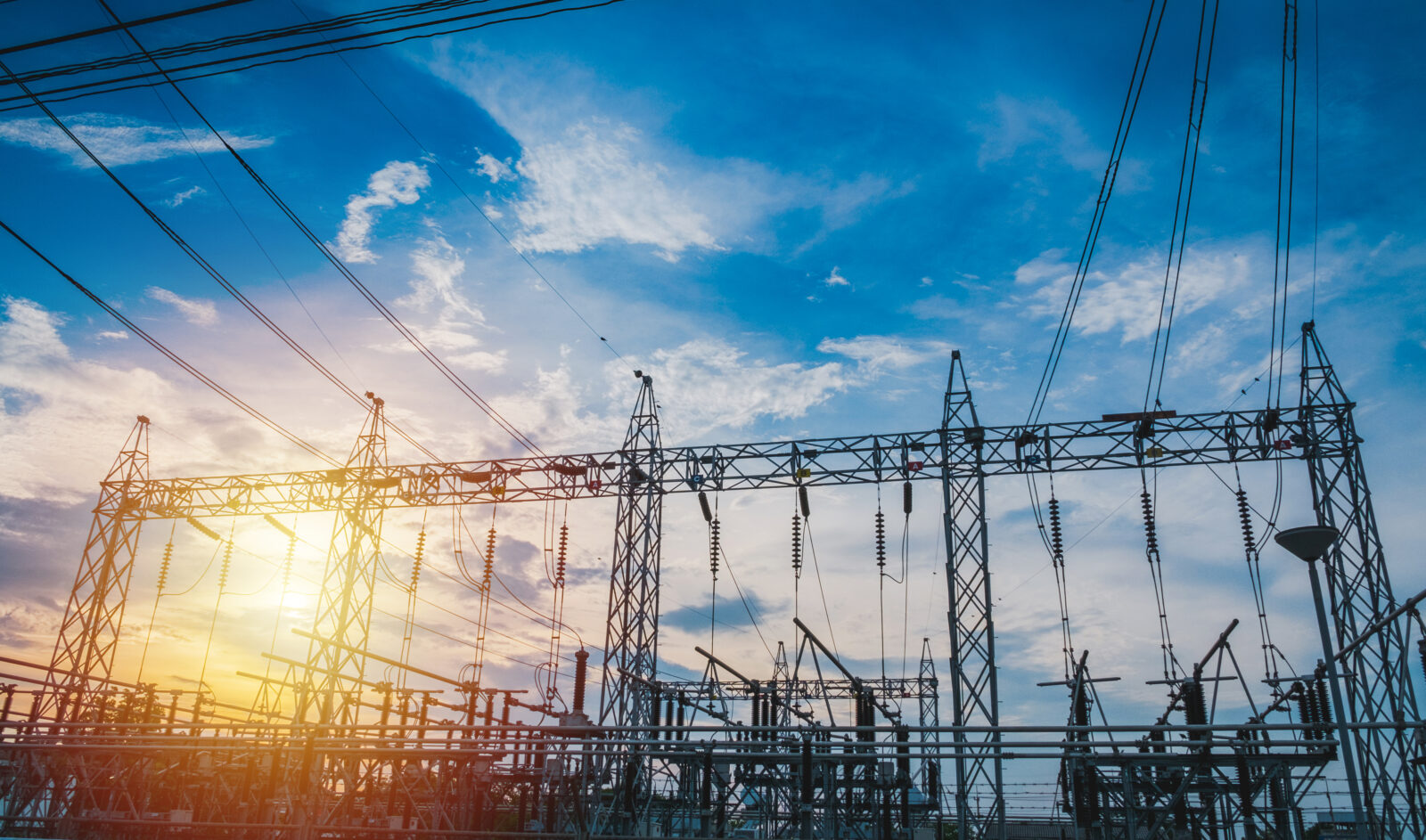 Electricity substation towers and power lines against a blue sky at sunset
