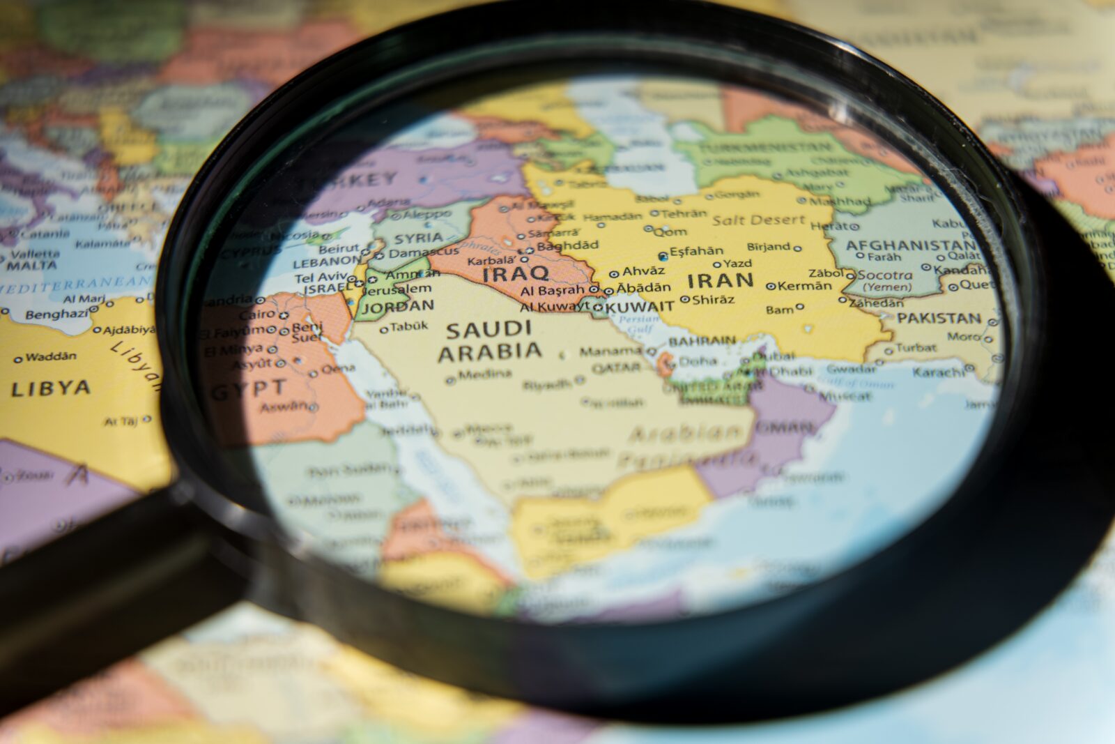 A magnifying glass over a coloured map of the Middle East, highlighting Saudi Arabia, Iraq and Iran