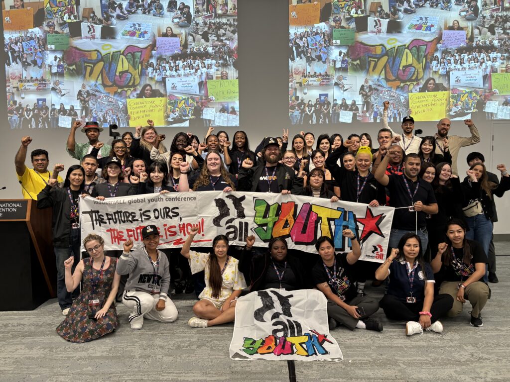 Young workers holding IndustriALL youth banners and raising fists at the Global Youth Conference in Sydney, November 2025.