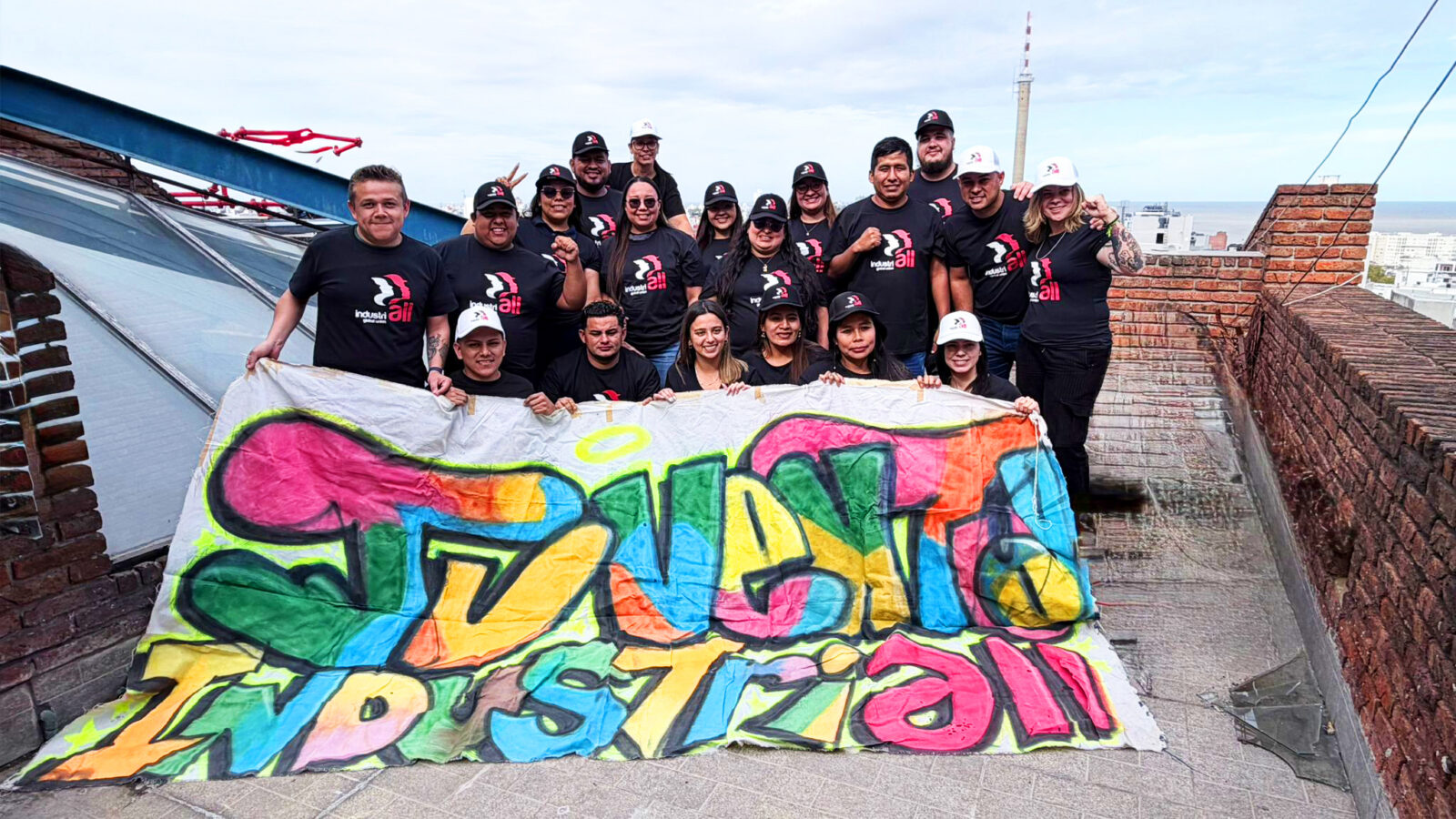 Young workers in IndustriALL t-shirts hold a colourful hand-painted banner reading "Juventud IndustriALL" on a rooftop in Montevideo, Uruguay