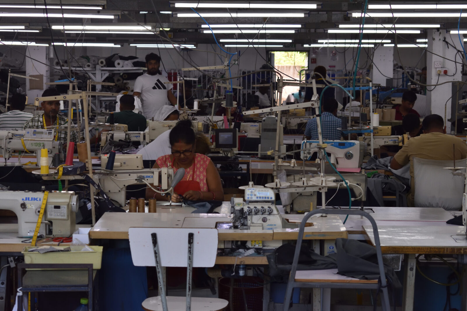 Trabajadoras migrantes de la confección en máquinas de coser en un activo piso de fábrica en Mauricio