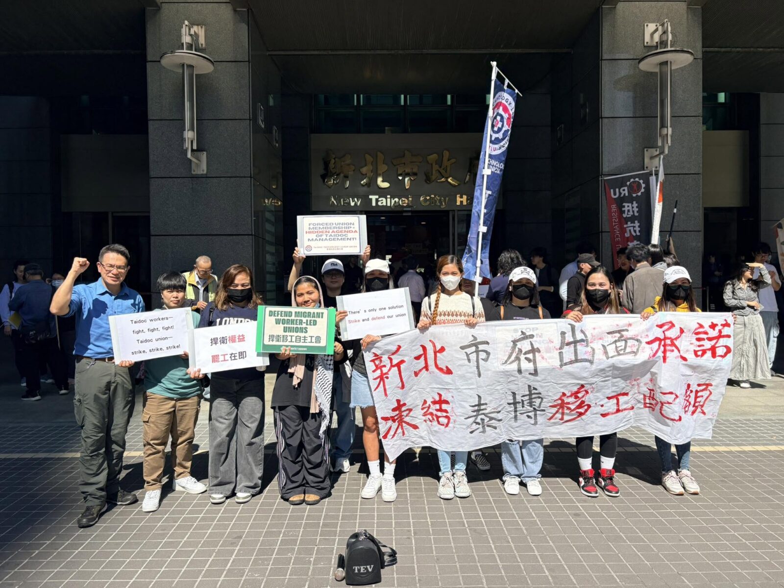 Migrant workers and union supporters protest outside New Taipei City Hall holding signs defending migrant worker-led unions and calling for strike action at Taidoc Technology Corp.