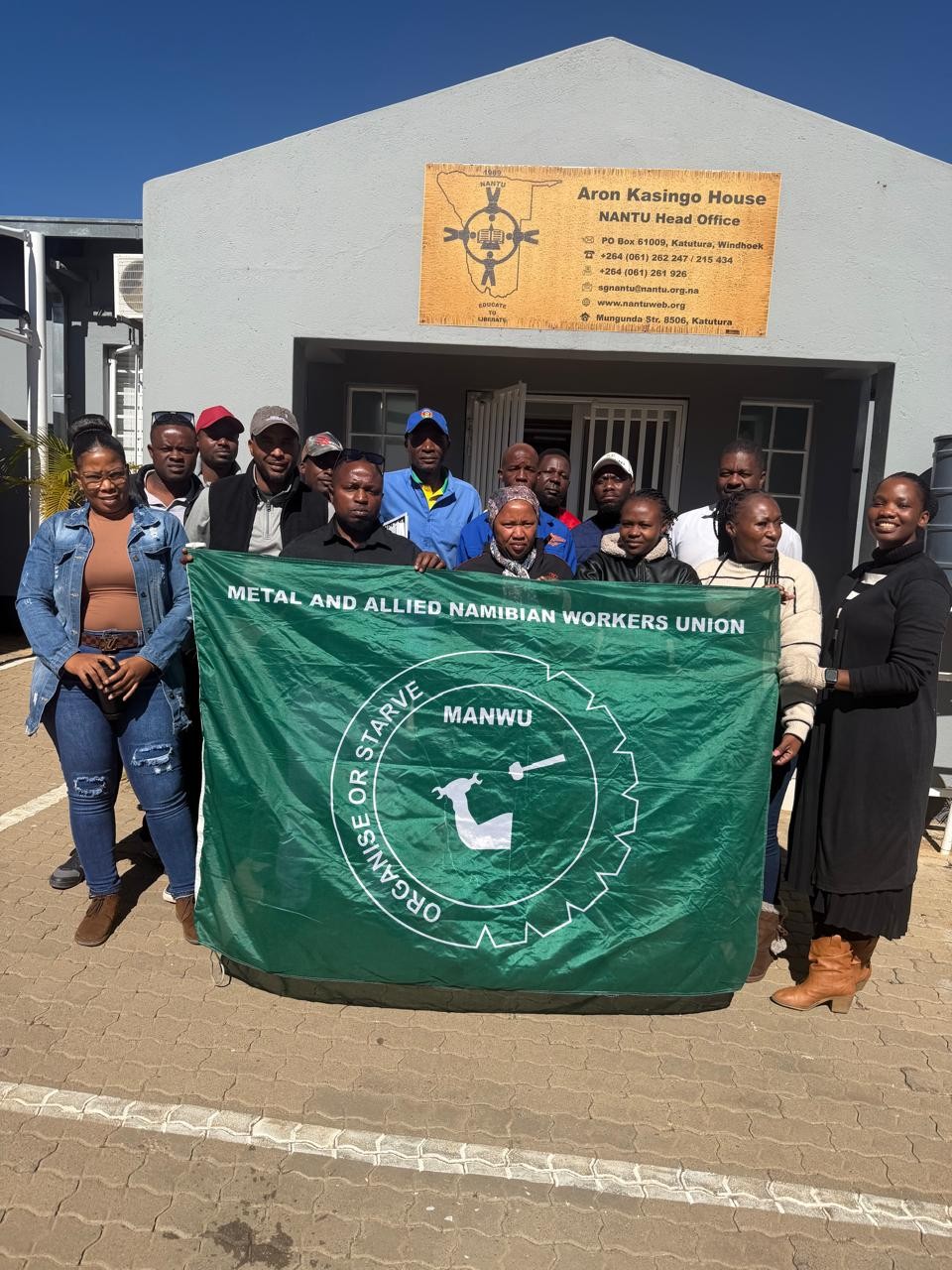 MANWU shop stewards hold union flag outside NANTU Head Office in Windhoek during automotive organising workshop, June 2026
