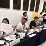 Monica Angelina holds up a handwritten sign during a workshop