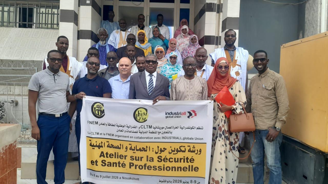 Group of Mauritanian trade unionists standing on building steps holding a CLTM, FNEM and IndustriALL banner for a health and safety workshop.