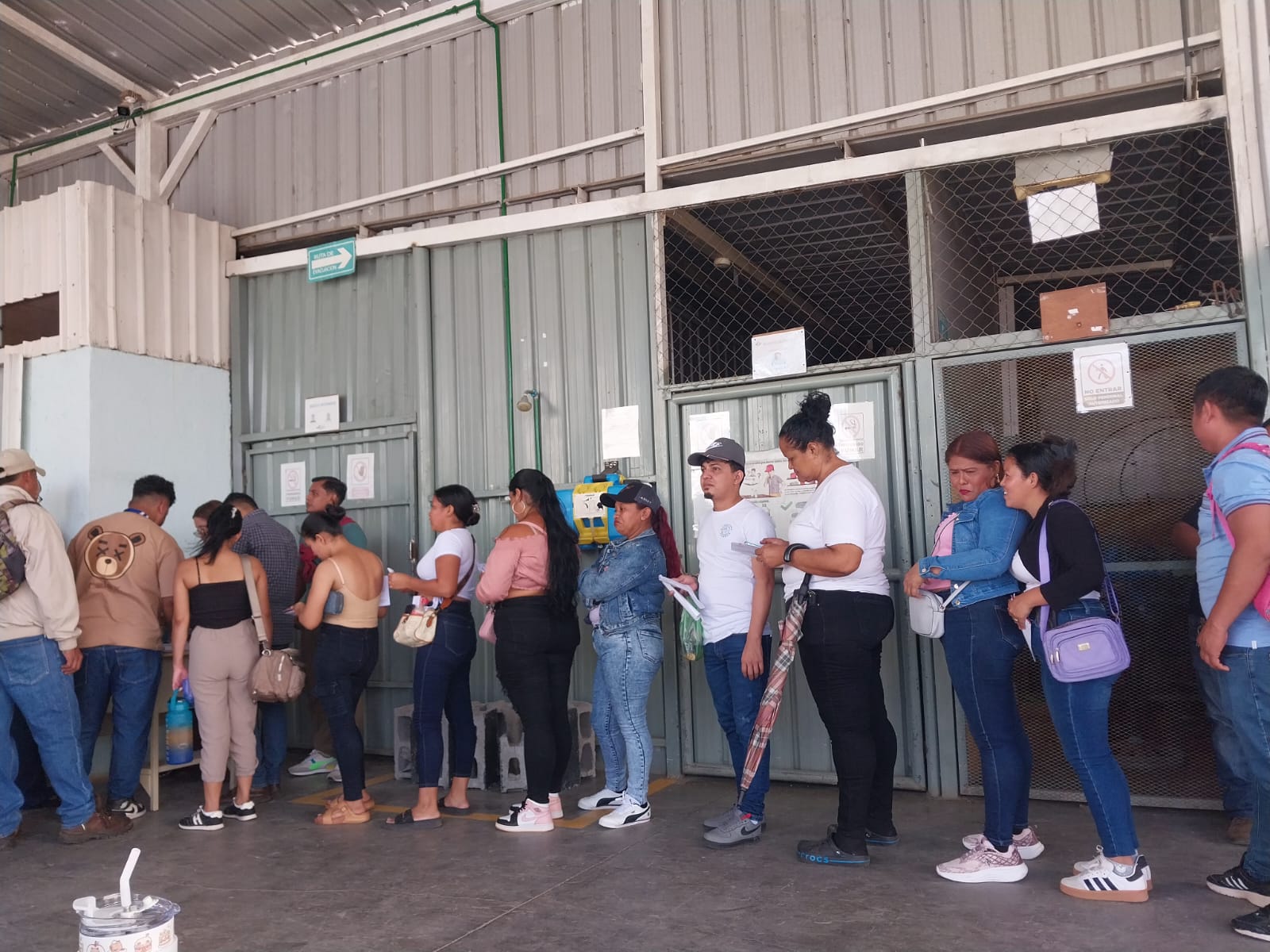 Extrabajadores de BTF esperan en fila para recibir el pago de sus prestaciones sociales en Nicaragua, como resultado del acuerdo logrado por FESITEX.
