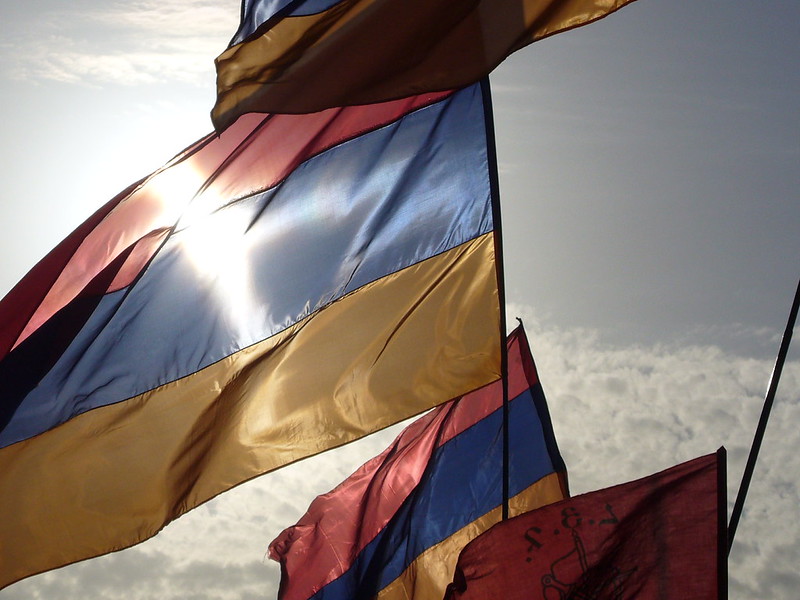 Close-up of waving Armenian flags backlit against cloudy sky