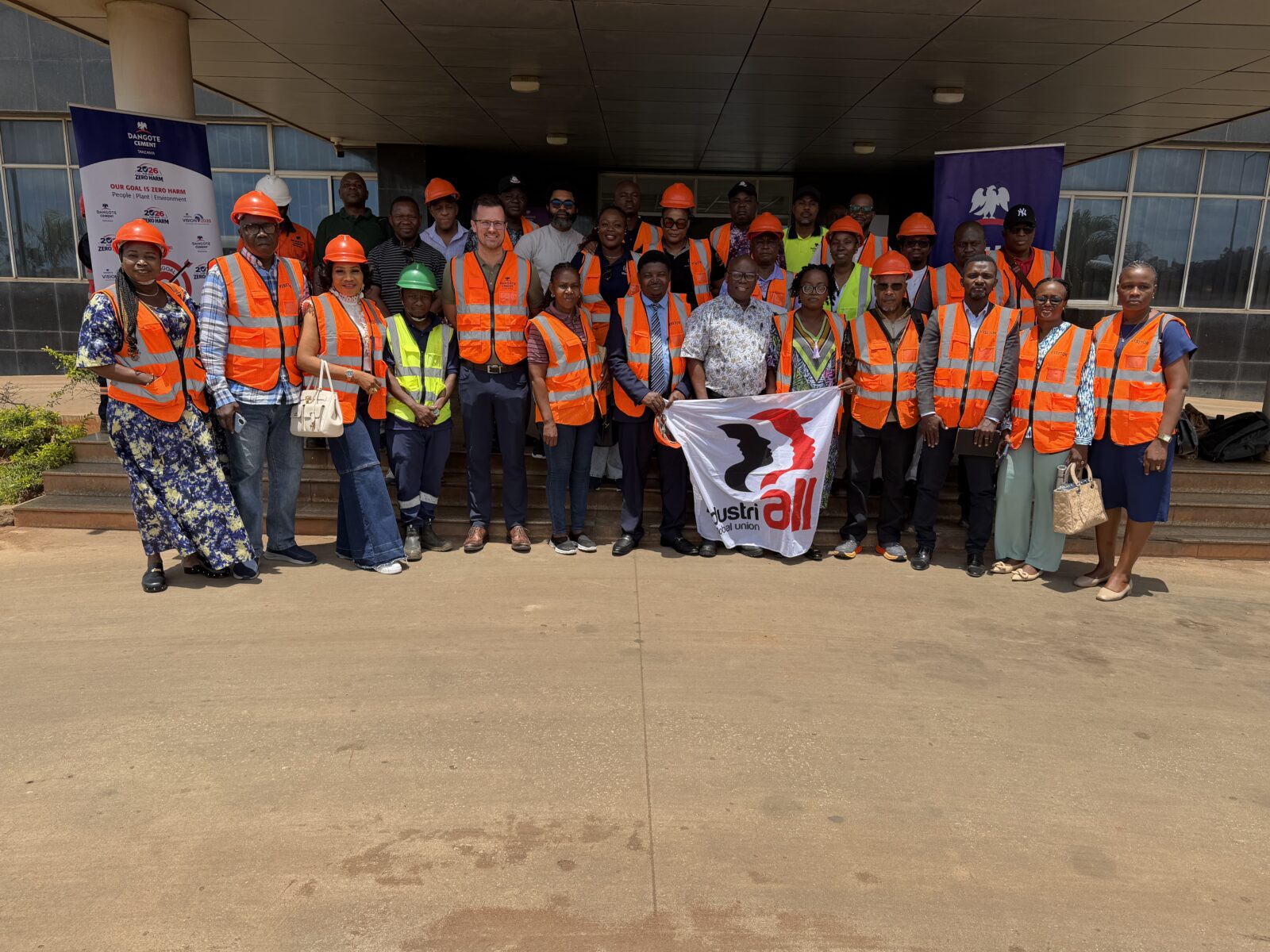 Delegates from the Dangote Trade Union Network wearing high-visibility vests and hard hats outside the Dangote Cement plant in Mtwara, Tanzania, holding an IndustriALL Global Union flag