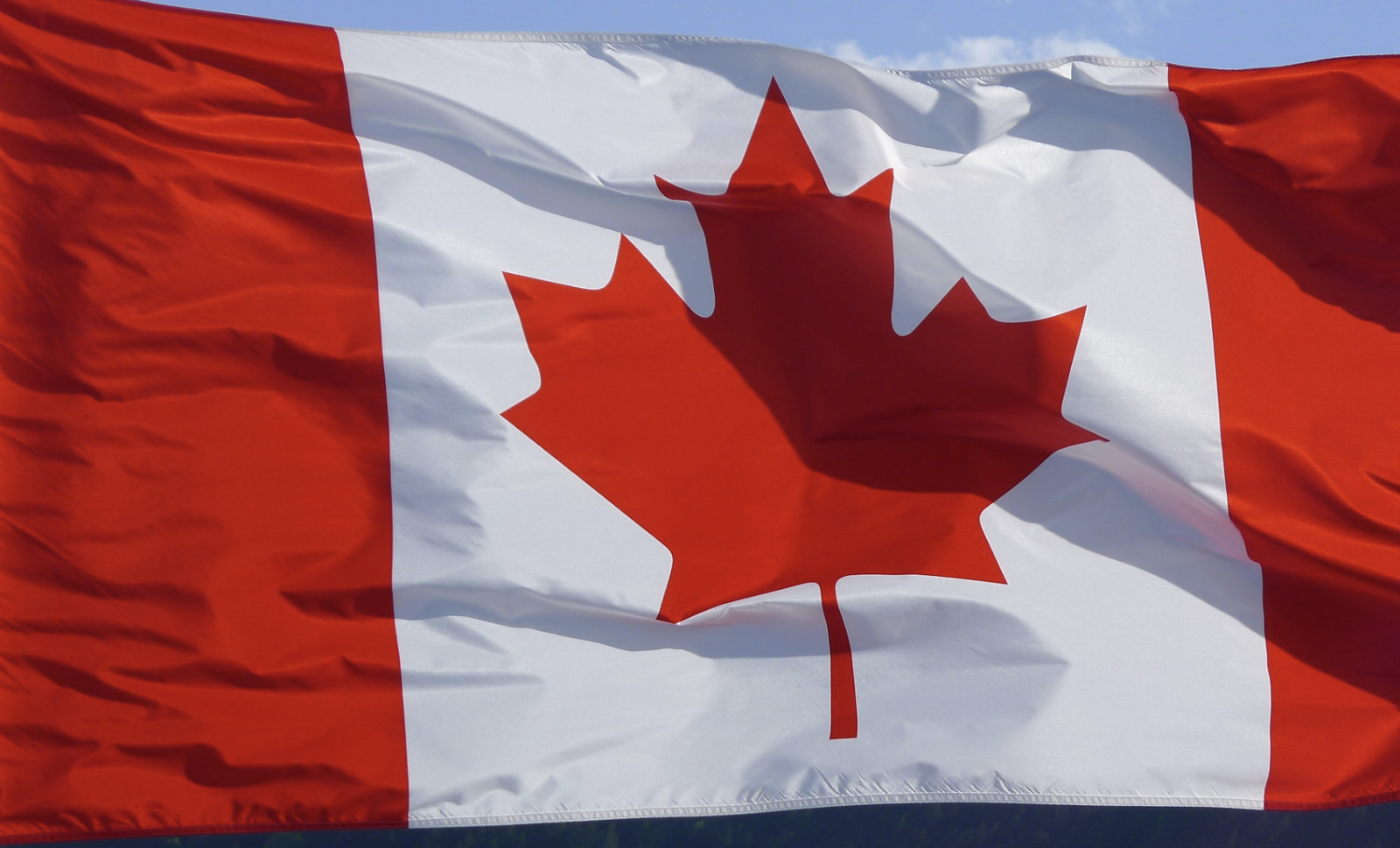 Canadian flag waving against a blue sky