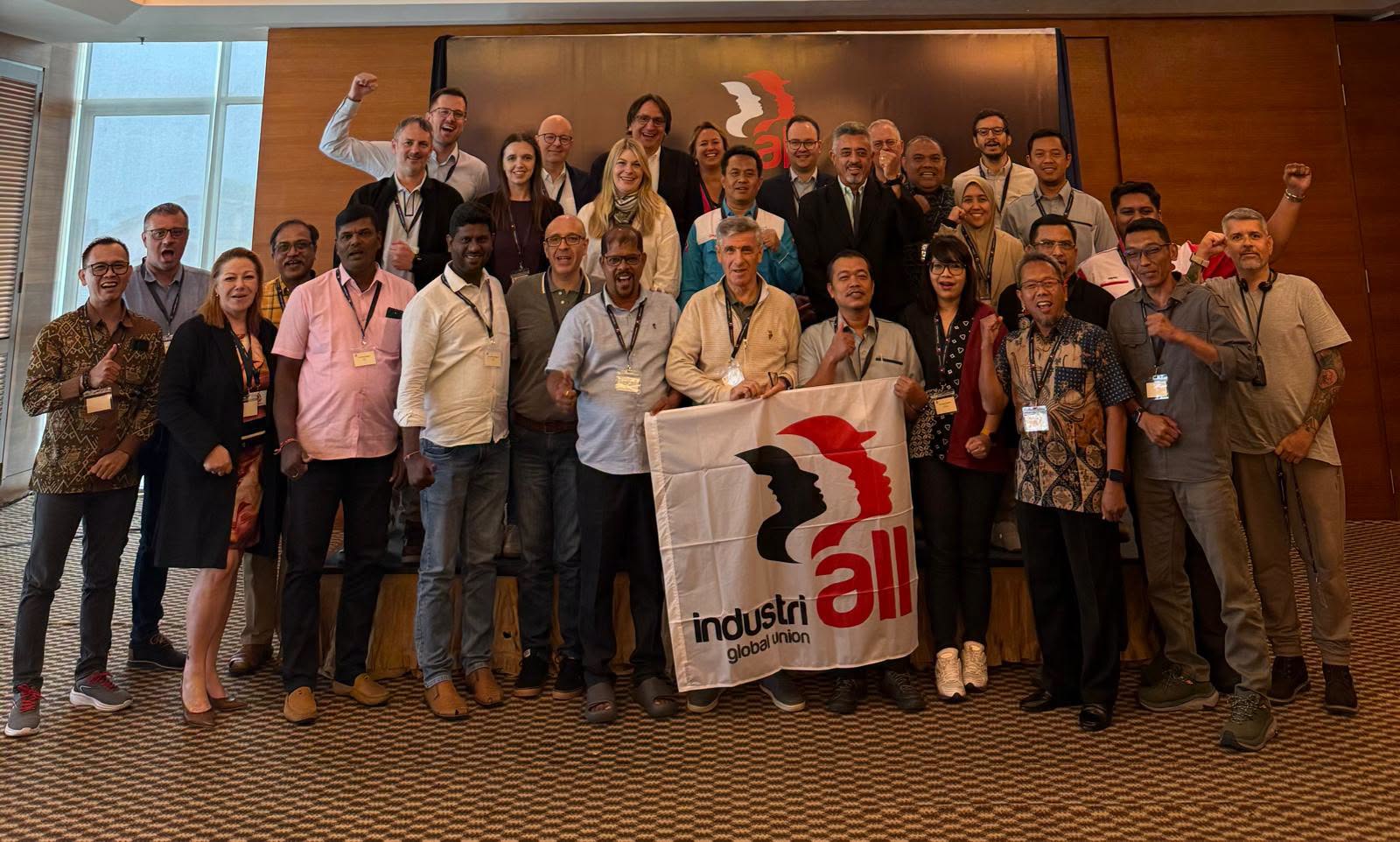Delegates of the BASF global trade union network raise fists and hold an IndustriALL flag at the group meeting