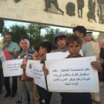 Участник акции протеста держит плакат с призывом отменить систему квот на места в правительстве