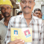 Рабочий в Мумбае показывает свою профсоюзную карточку, на которой указана его группа крови.