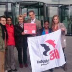 Adam Lee, Directeur de syndicalisation et de campagnes pour IndustriALL, tenant dans les mains une pétition signée par plus de 100 000 personnes devant la façade de l’immeuble où a eu lieu l’Assemblée générale annuelle d’Hugo Boss à Stuttgart.