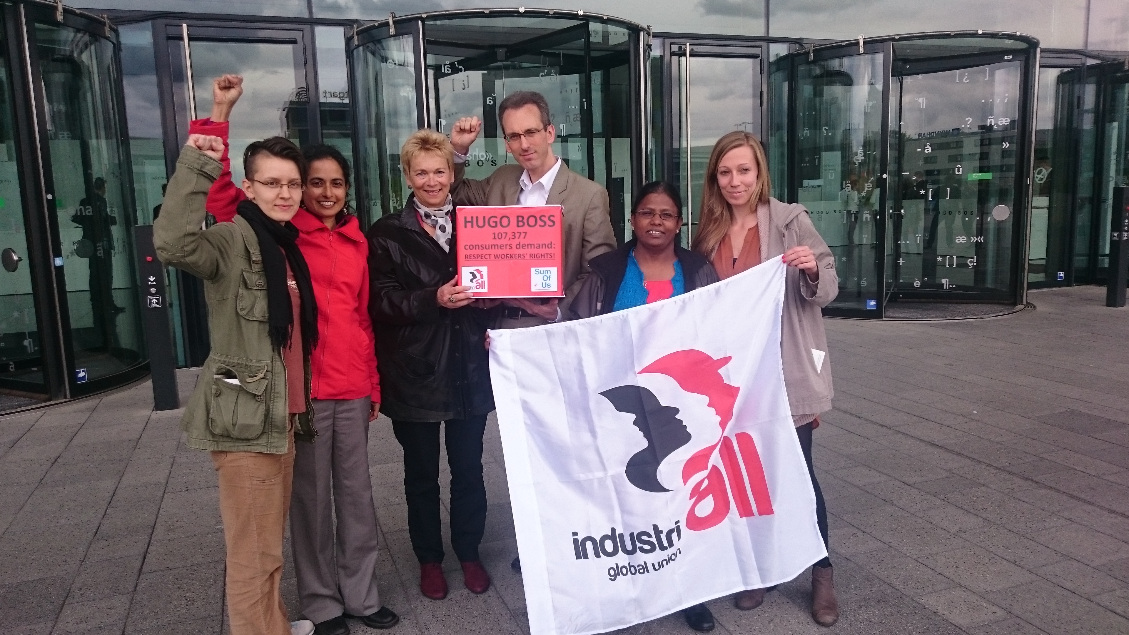Adam Lee, Directeur de syndicalisation et de campagnes pour IndustriALL, tenant dans les mains une pétition signée par plus de 100 000 personnes devant la façade de l’immeuble où a eu lieu l’Assemblée générale annuelle d’Hugo Boss à Stuttgart.
