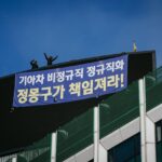 За митингом наблюдают два субподрядных рабочих Kia. Они находятся на крыше небоскреба в Сеуле с июня 2015 года, требуя у автомобильной компании перевести временных работников на постоянную форму занятости. Фото: IndustriALL/Джун Майкл Парк.