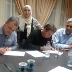 Тахар Бербери (слева) подписывает соглашение с президентом федерации работодателей (второй слева) в министерстве социального обеспечения в Тунисе.