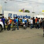 Dismissed workers gather in front of Electrolux plant in Thailand