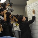 Представитель JCM пишет на доске ответное предложение по повышению заработной платы 